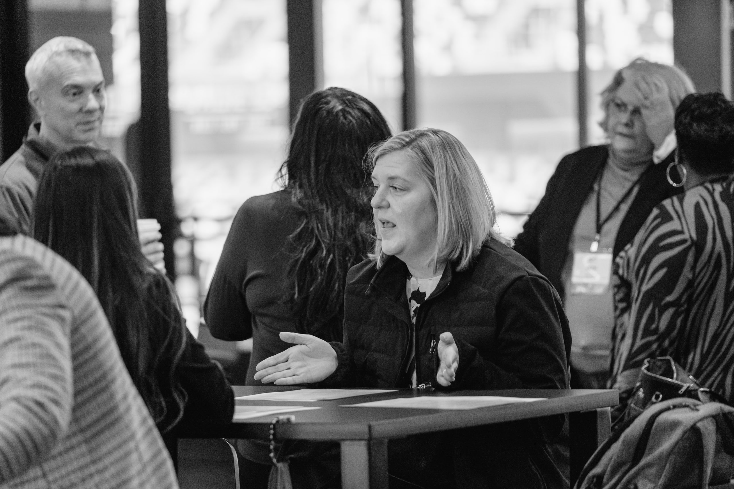 B&w group around a table, real conversation.