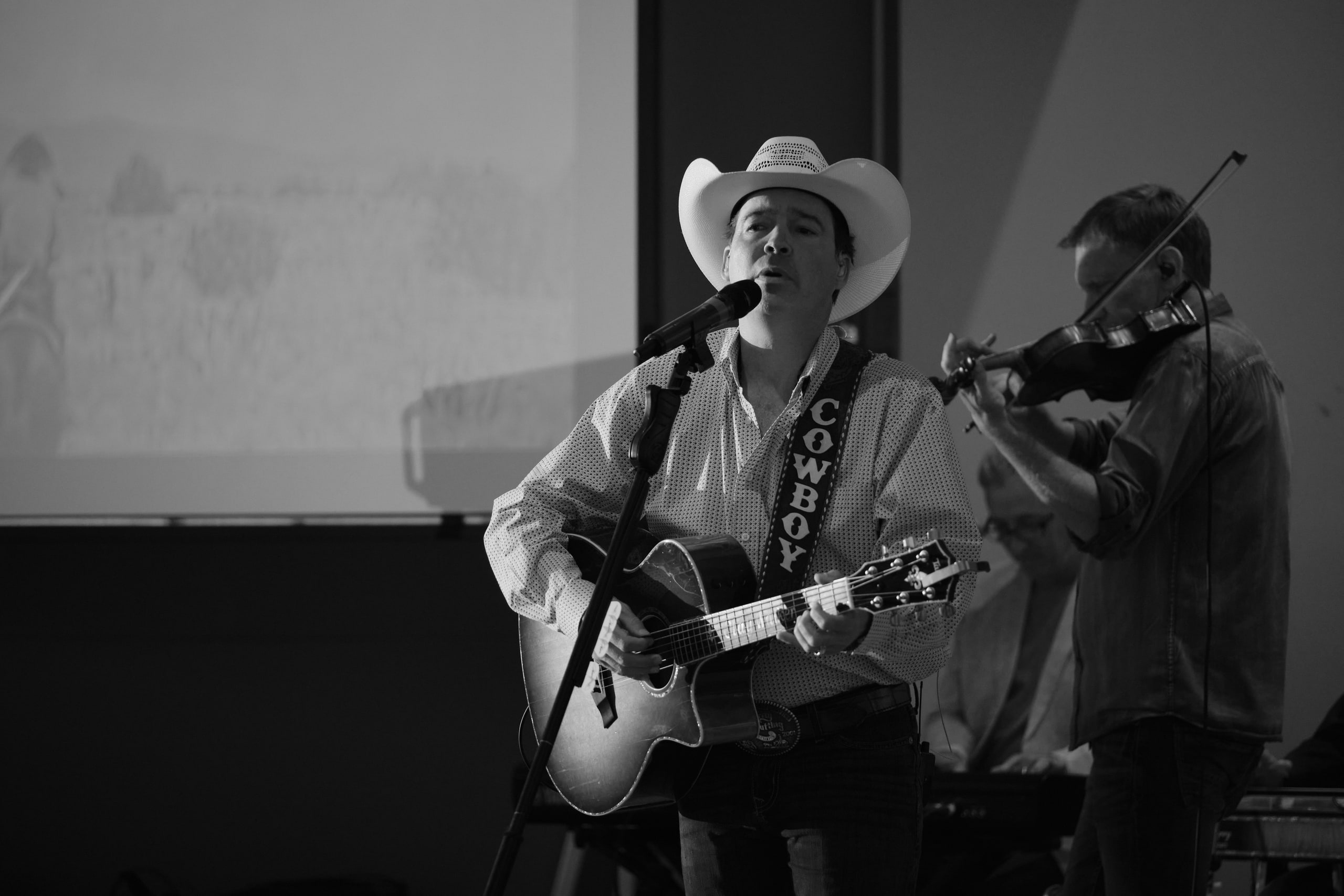 Black and white singer with the hat and fiddle at a community event.