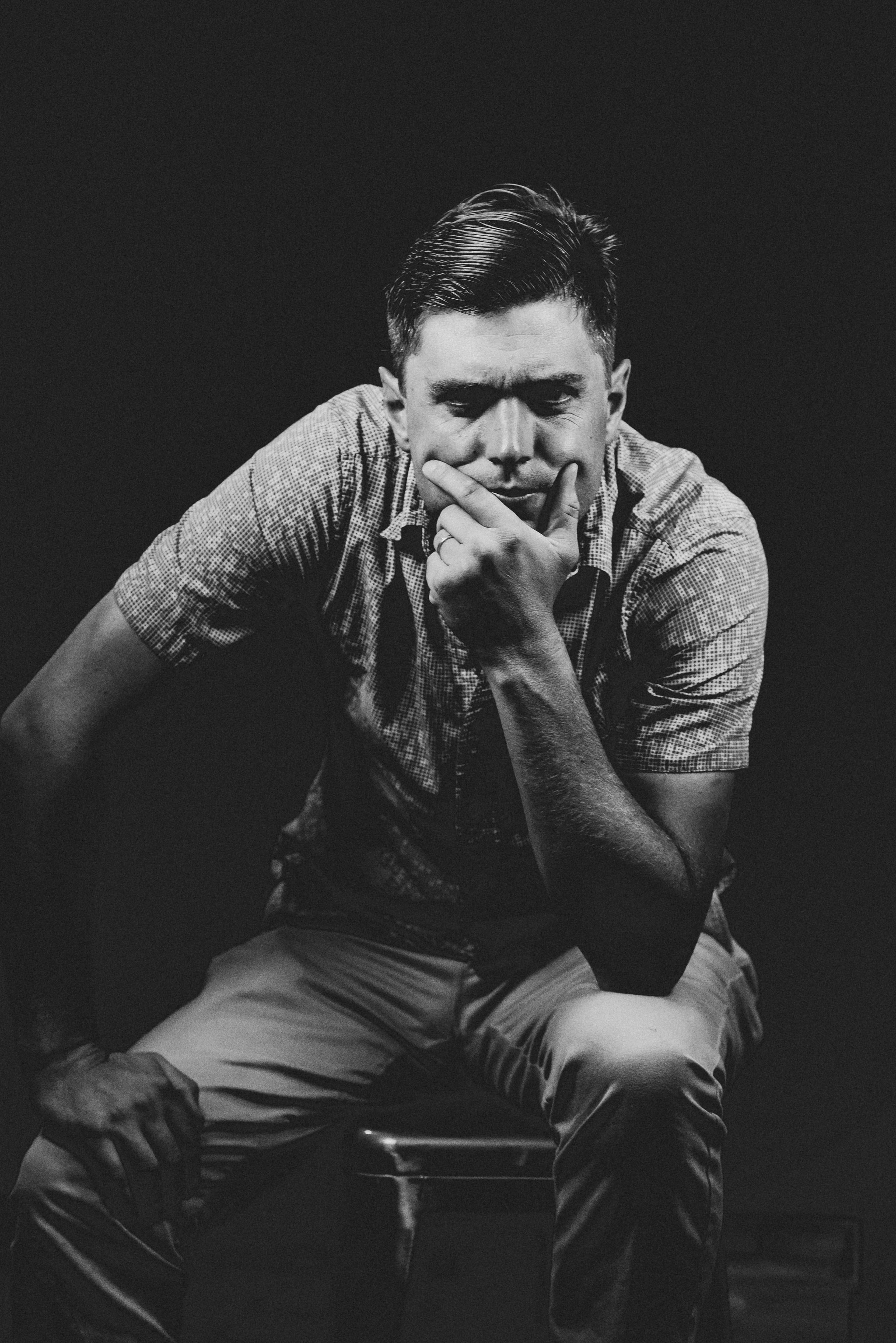 B&w seated, thinking, hands in it.