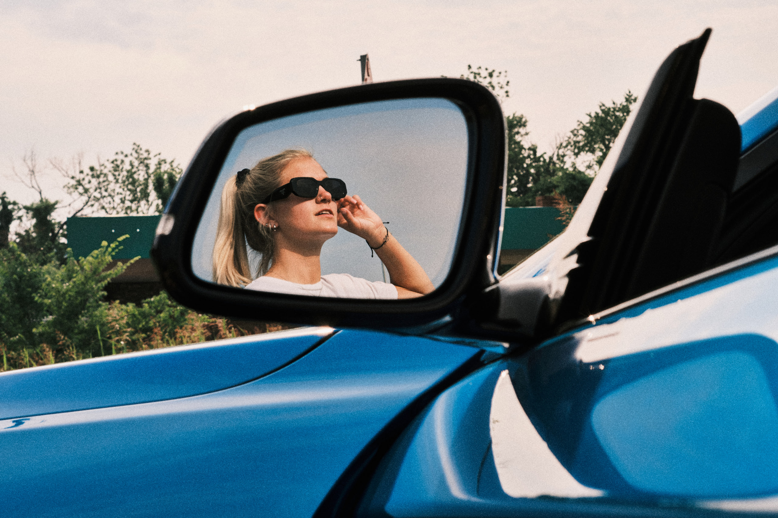 The driver in the wing mirror, blue door, sunglasses.