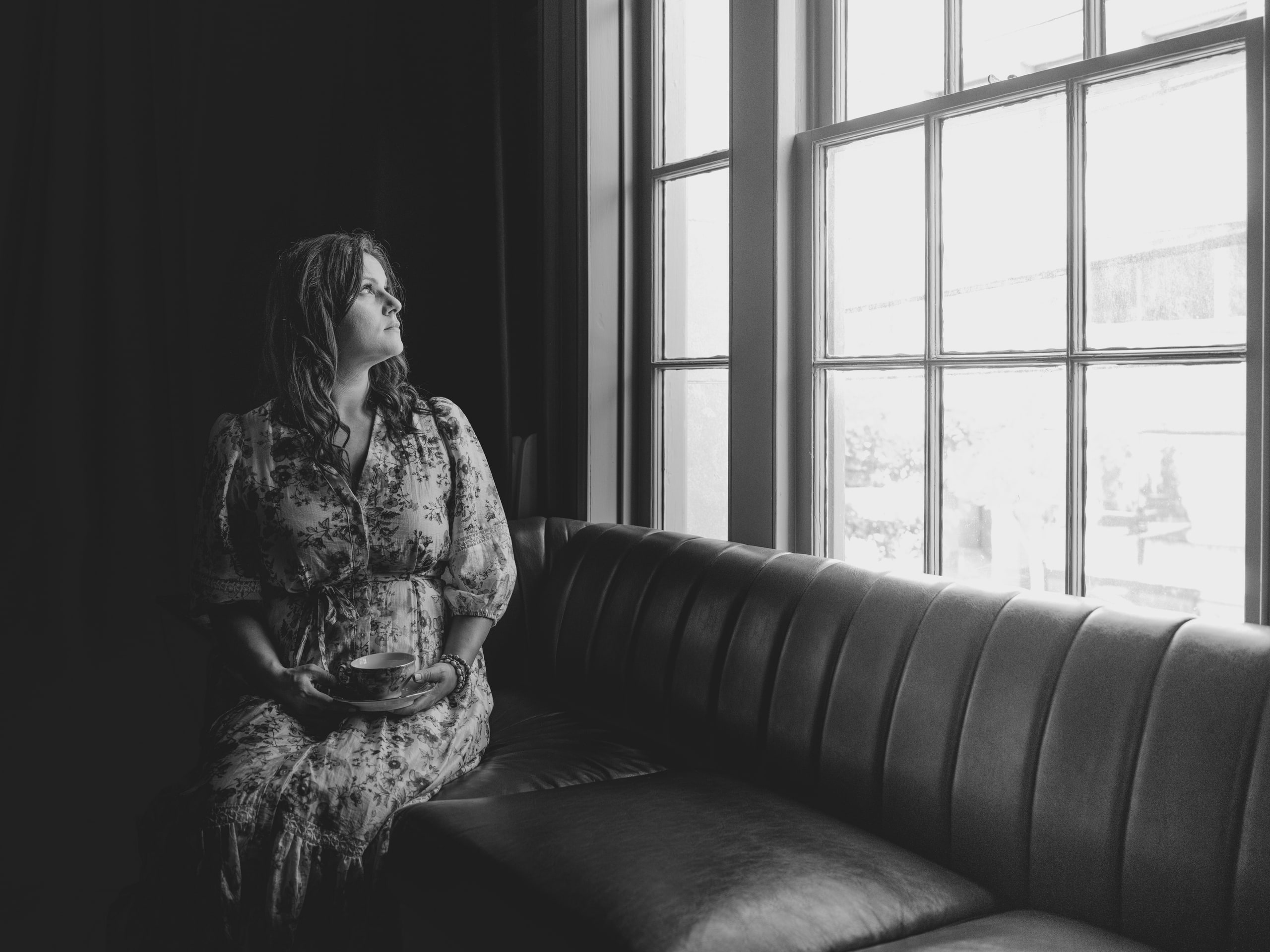 A woman seated on a sofa in window light, black and white, at The Exchange on Loudoun.