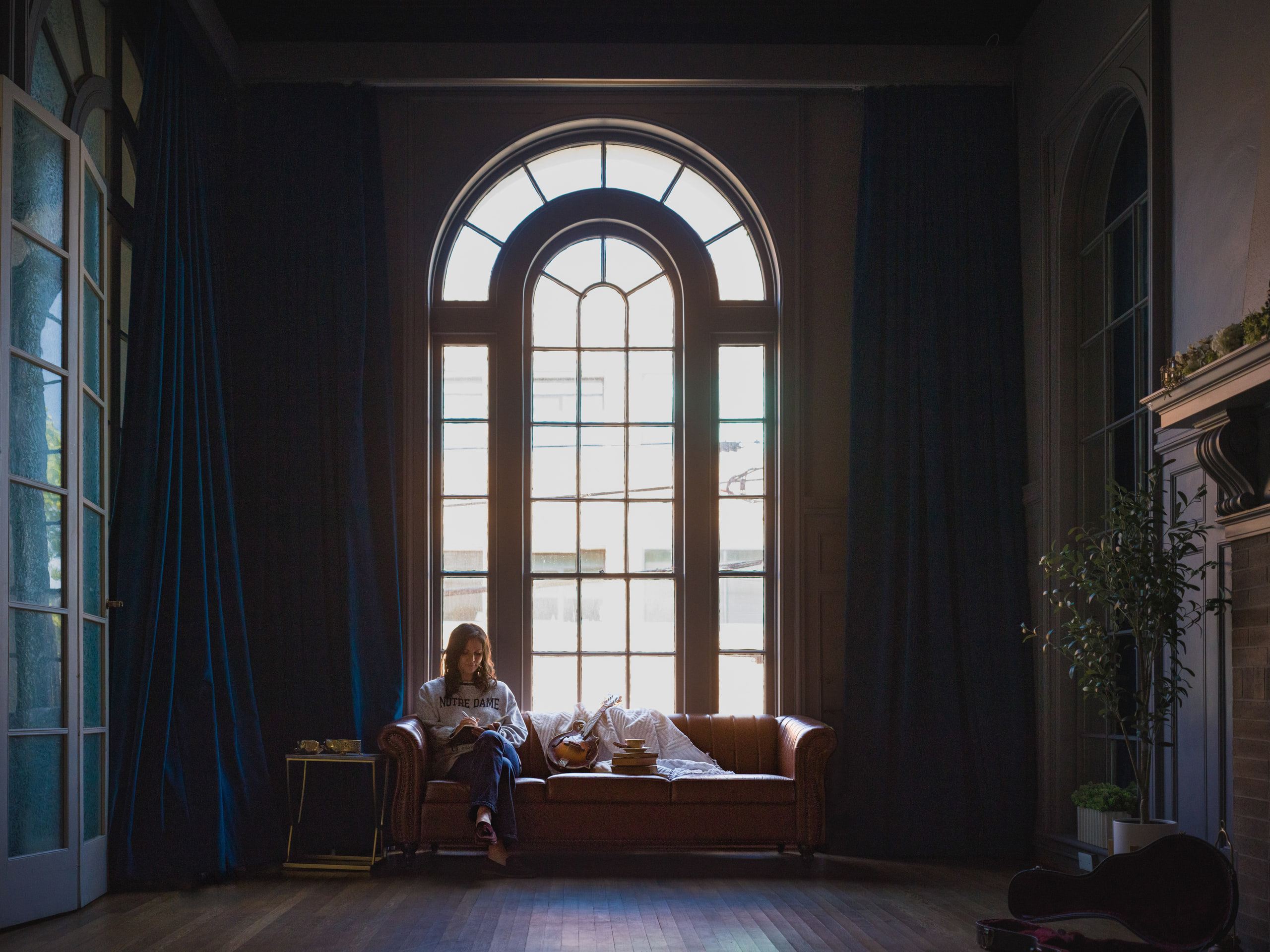 A musician seated small in the arched window room with blue drapes at The Exchange on Loudoun.