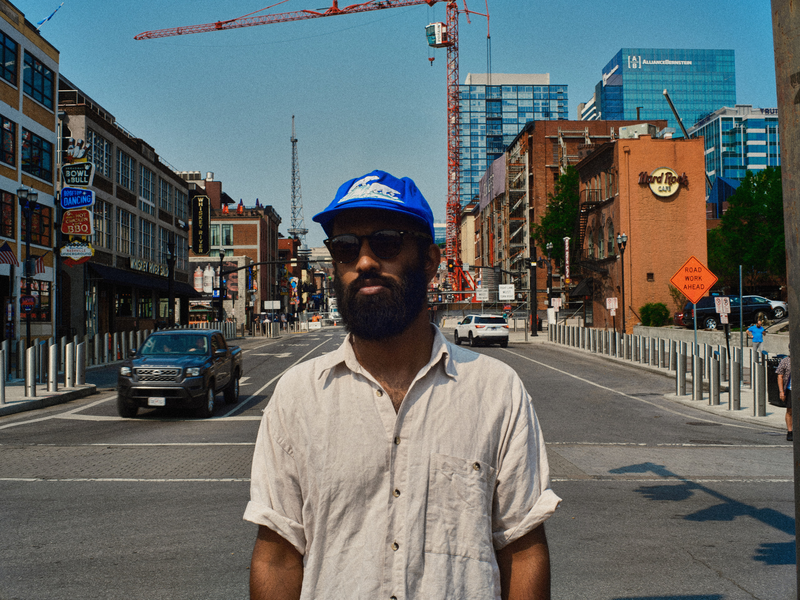 Standing in the road, blue cap, city behind in downtown Nashville.