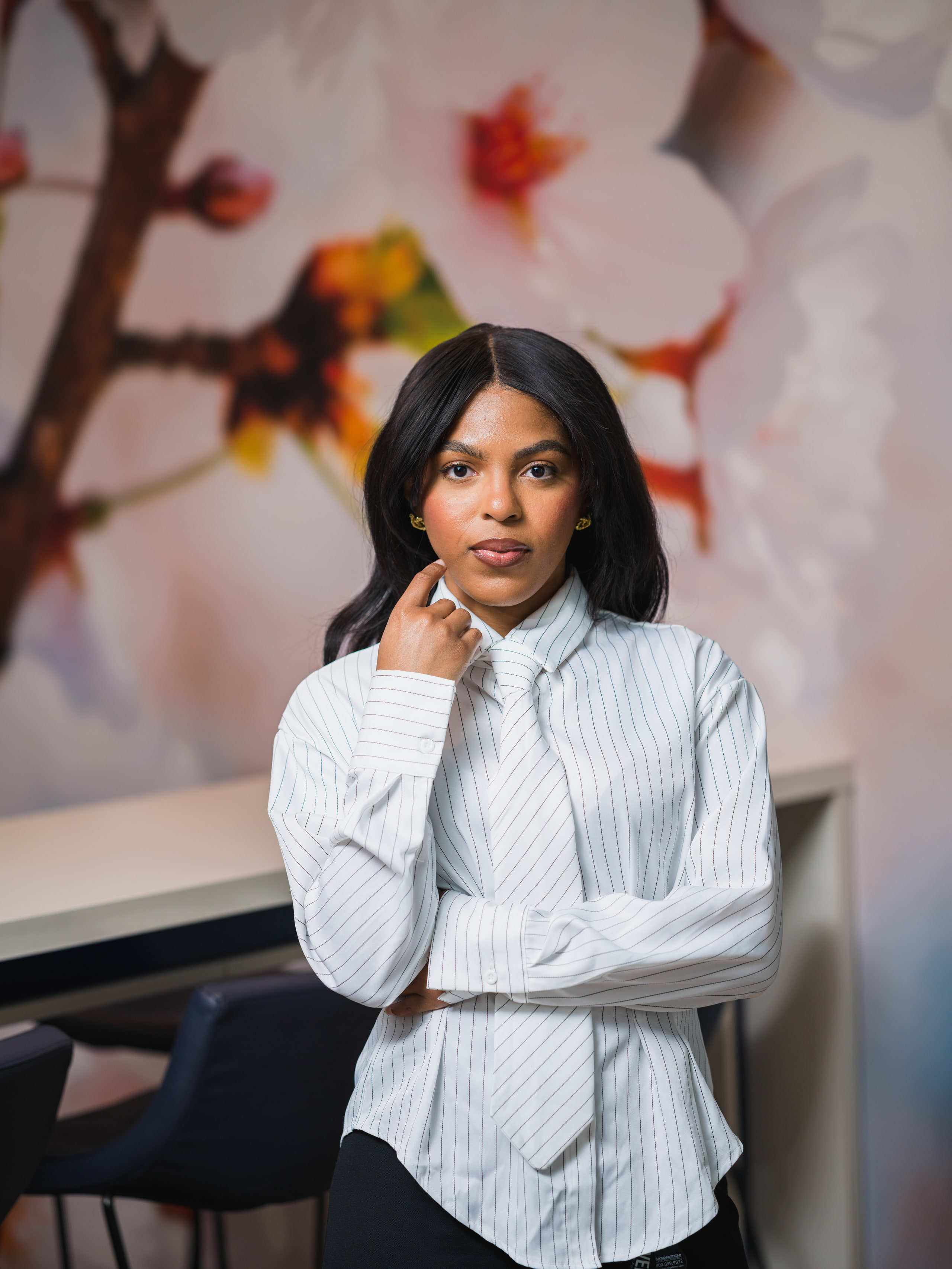 A portrait of a woman in a white blouse, hand at her chin, from an on-site portrait day.