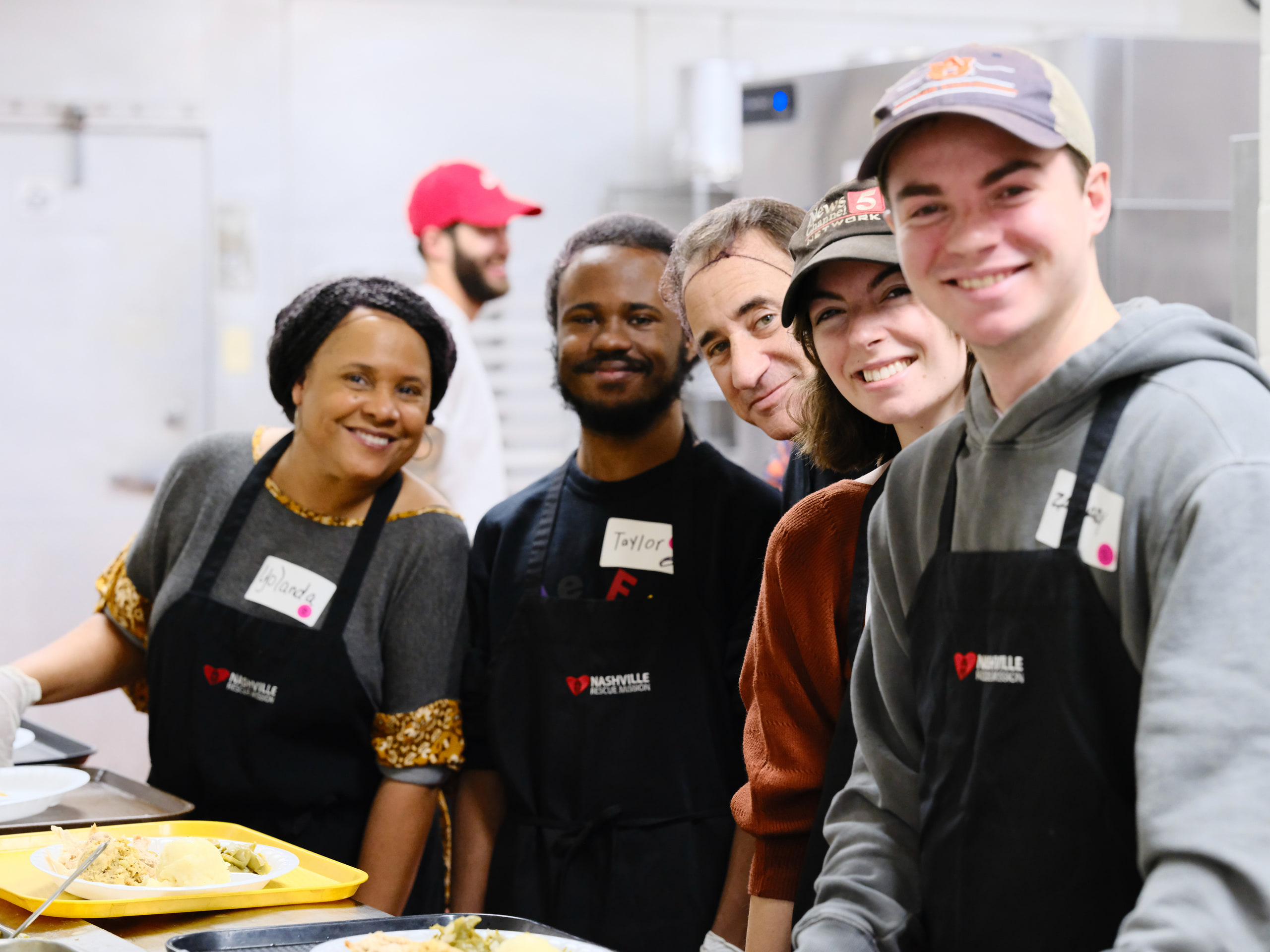 Five volunteers at the line, group at a community event.