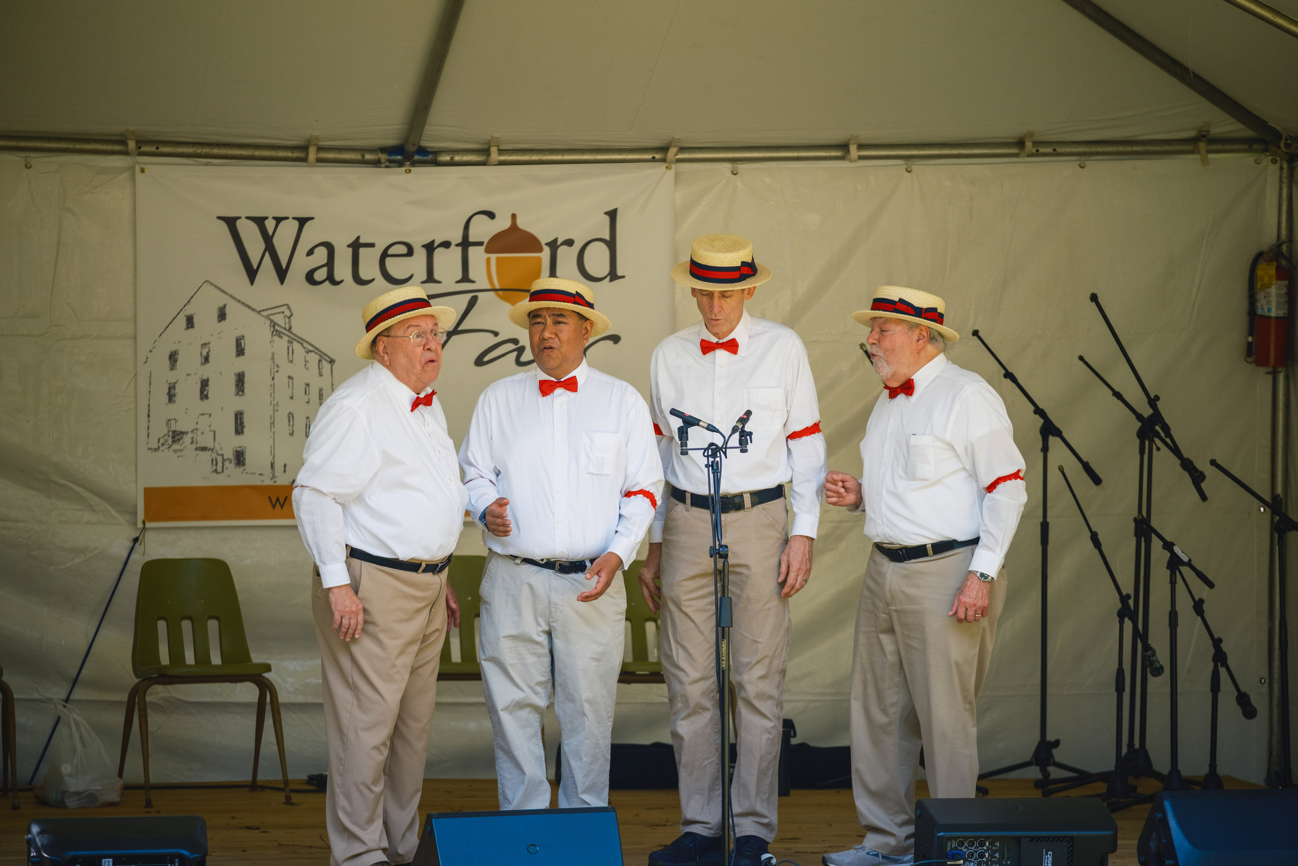 A barbershop quartet in straw boaters, white shirts and red bow ties singing on the Waterford Fair stage.