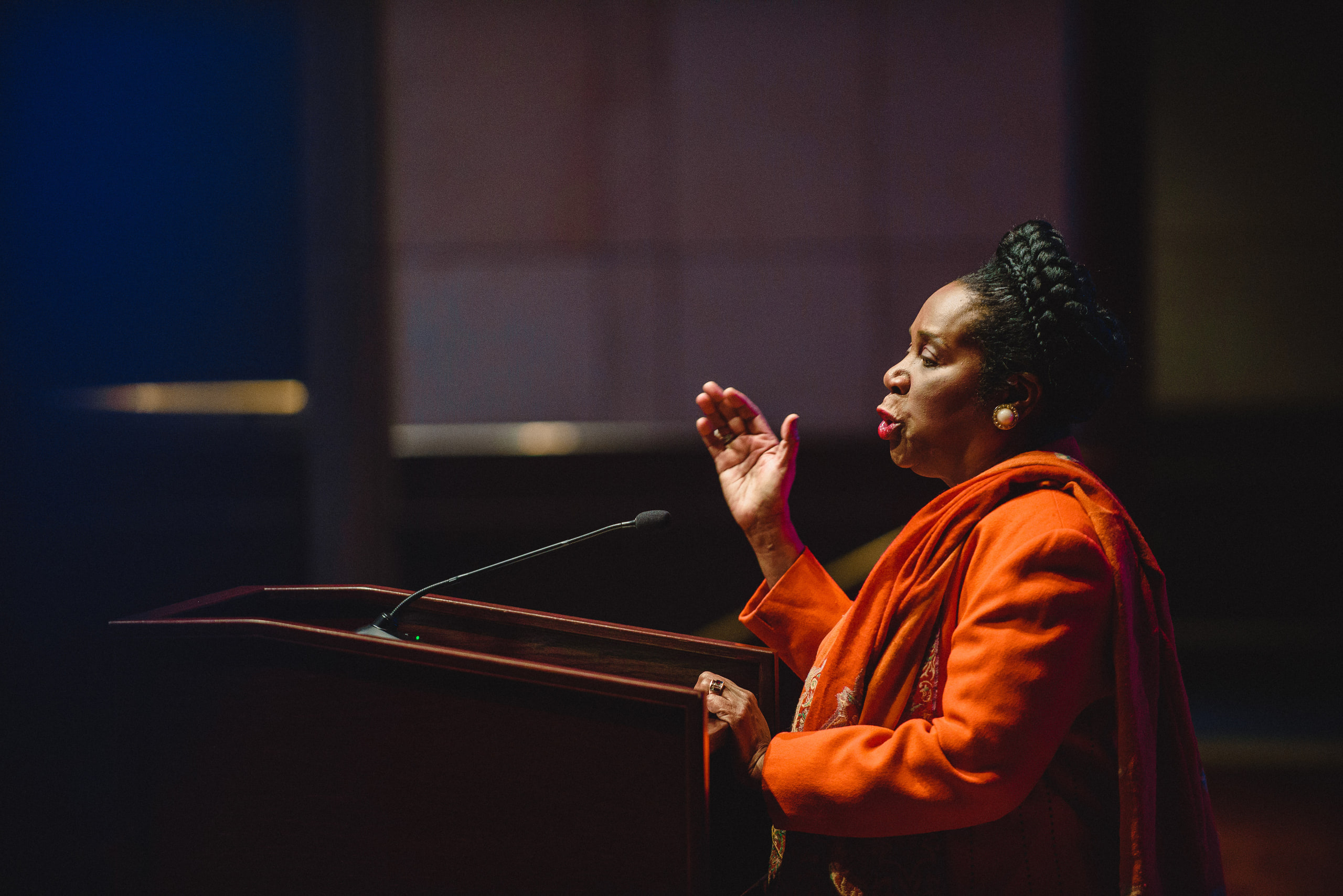 Speaker in red at the mic, warm at a conference in Washington, DC.