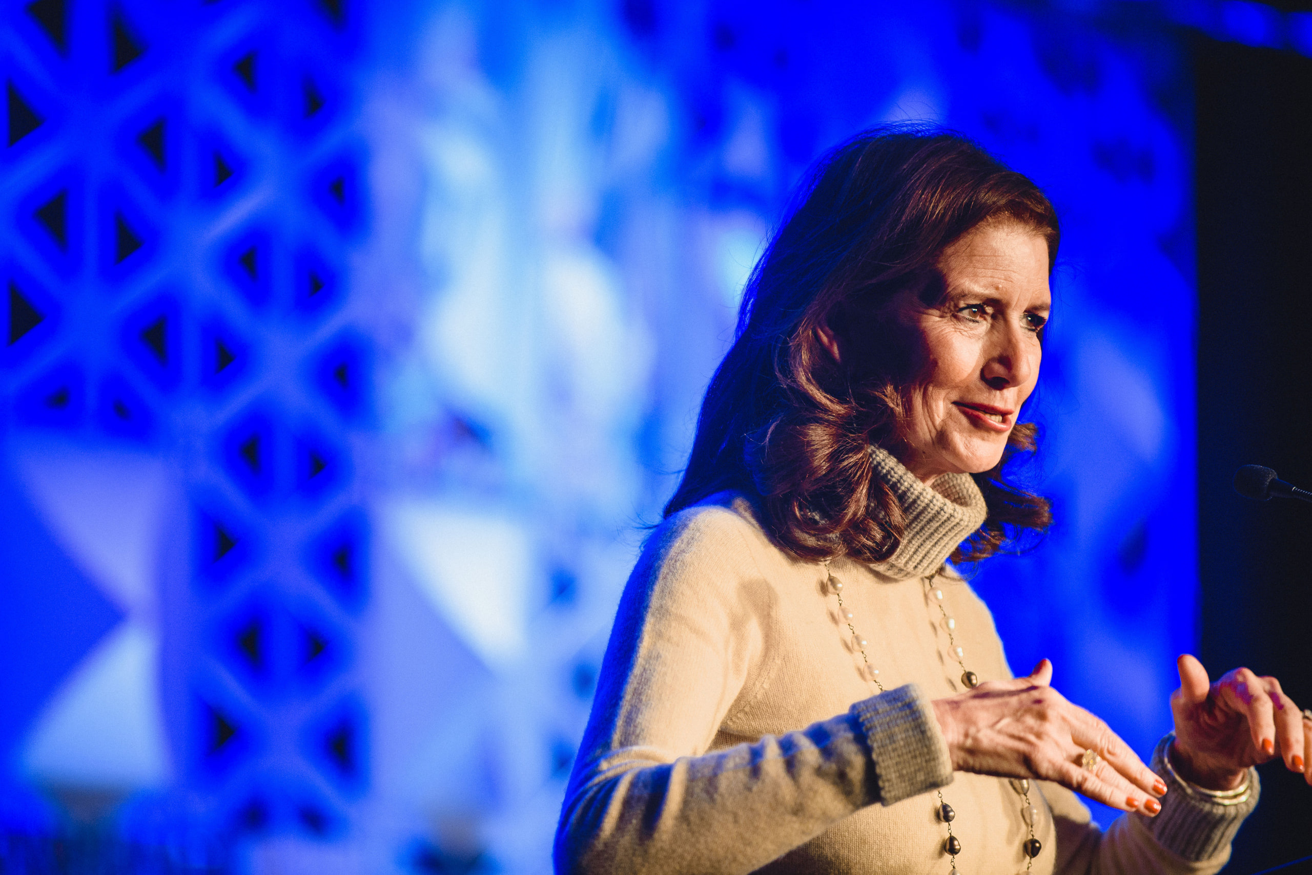 Speaker in white, blue set, portrait at a conference in Washington, DC.