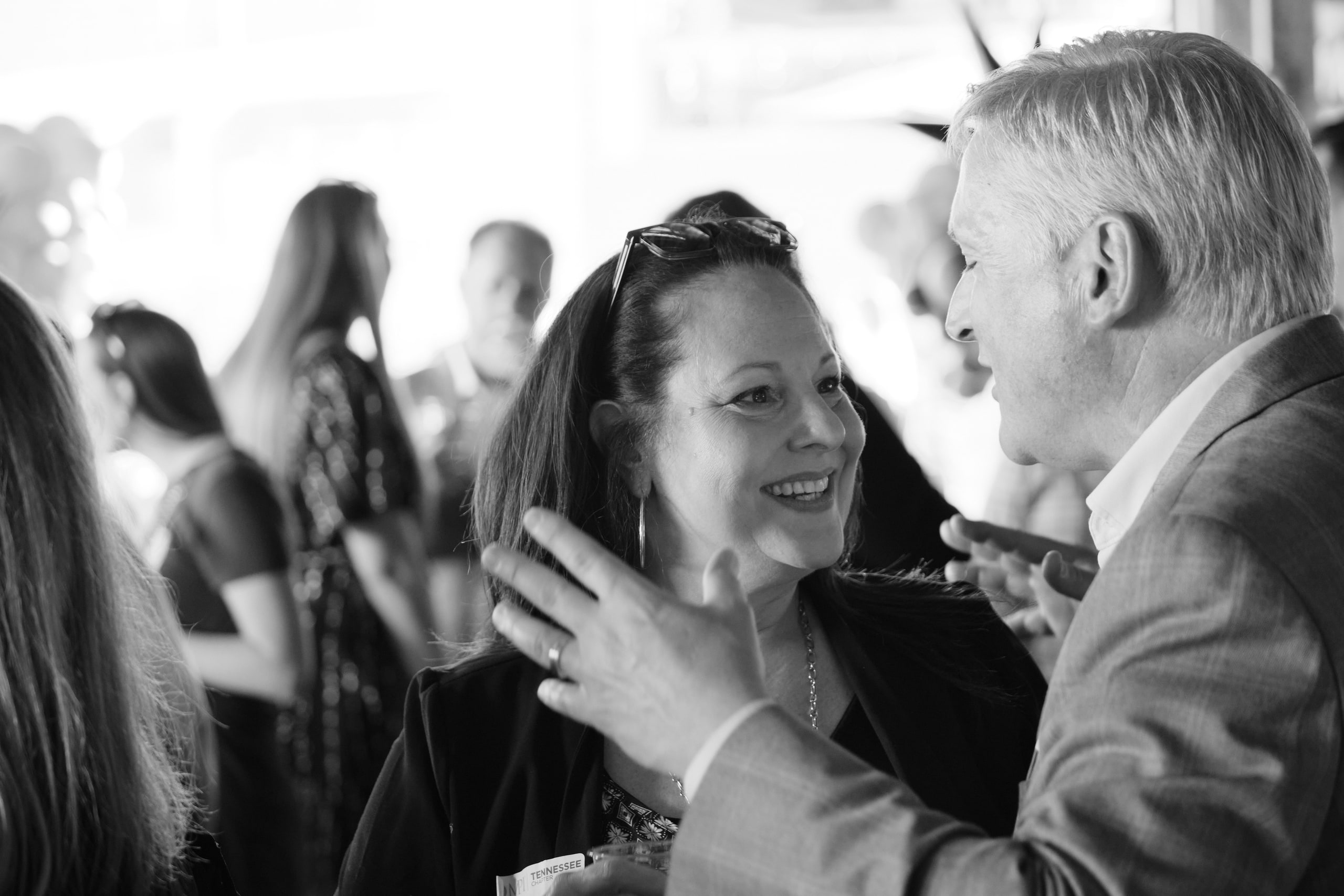 Black and white: two guests greeting each other warmly in the crowd at an industry mixer