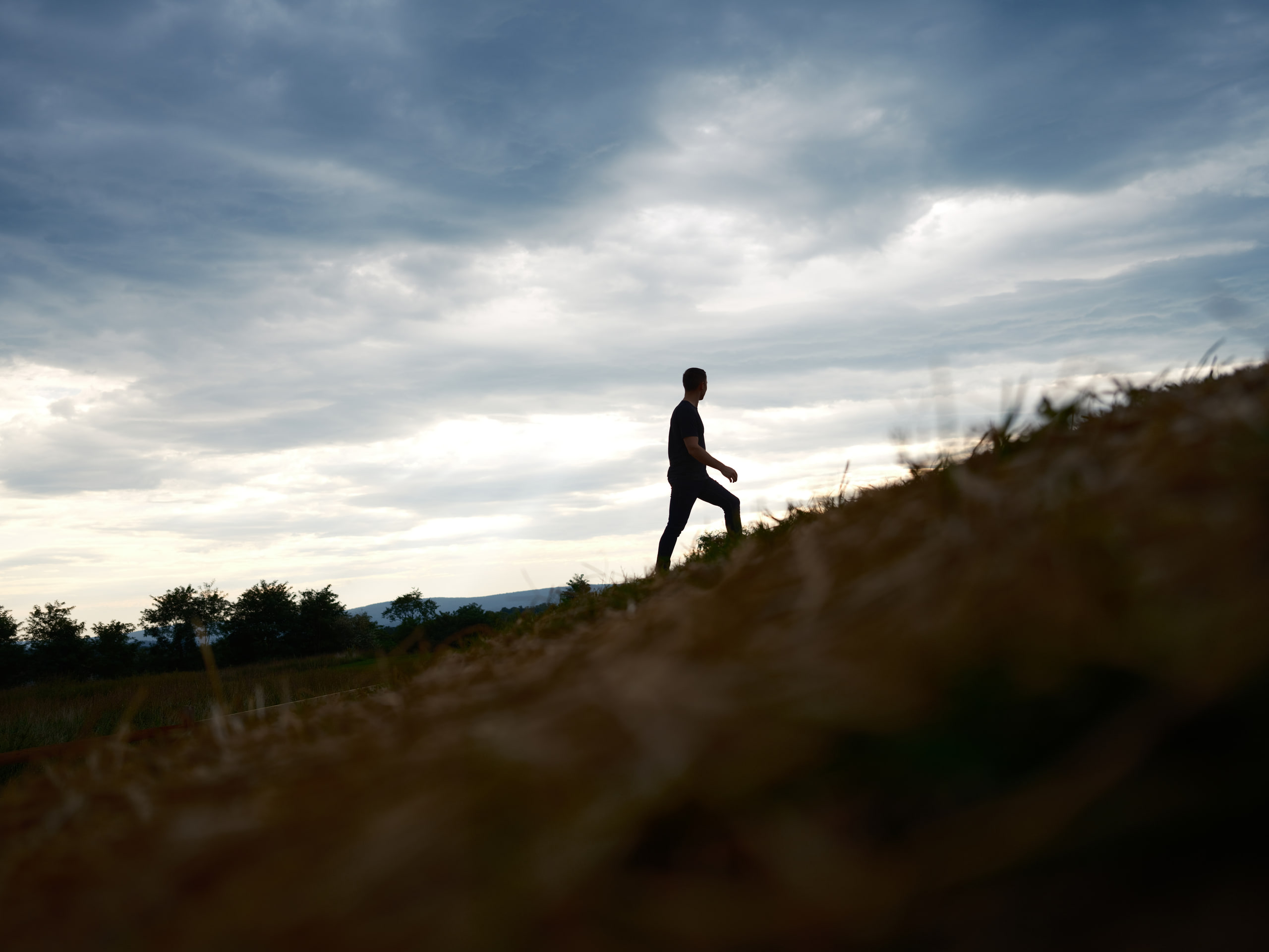 Figure on a ridge against storm cloud, tiny and clear.