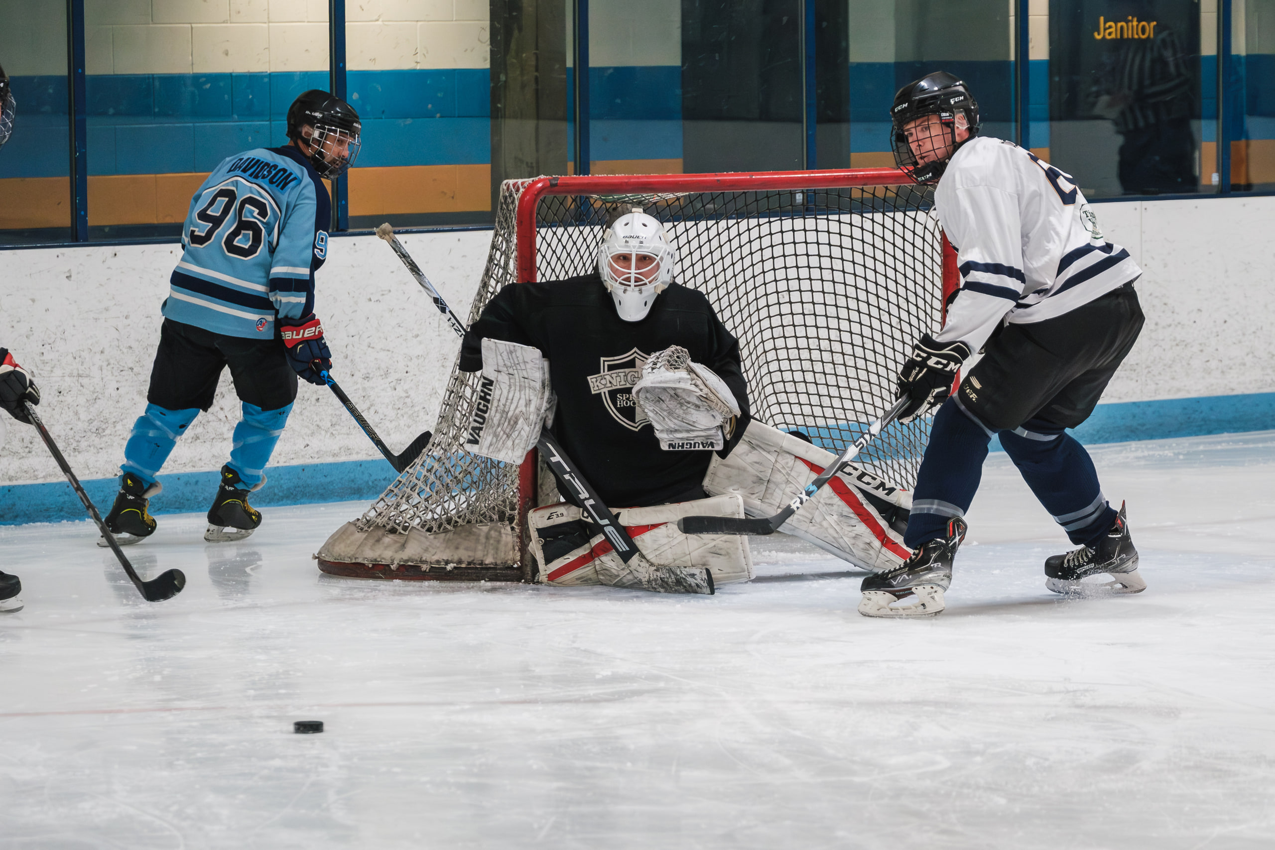 Goalie in the crease, bodies around the net.