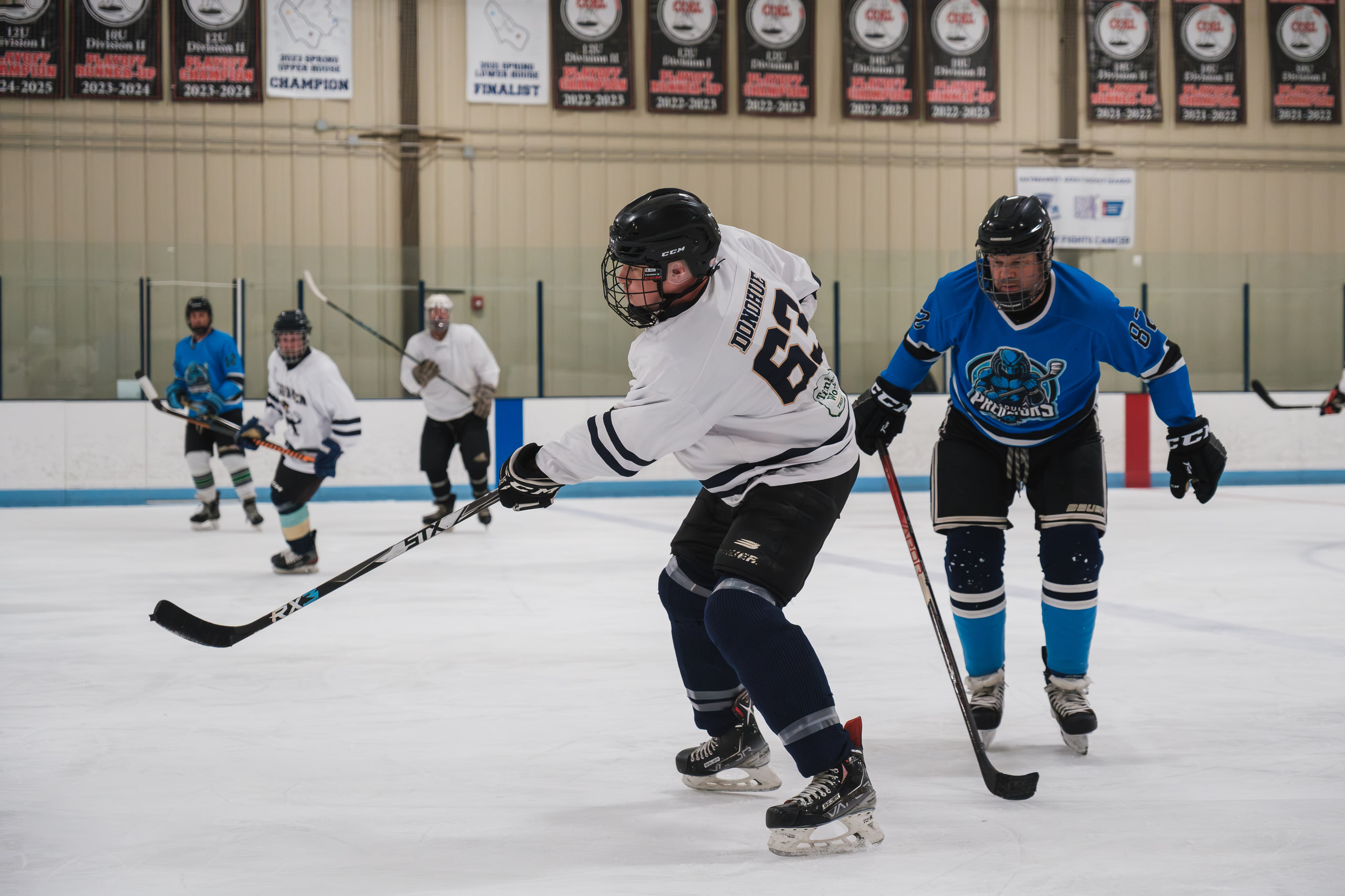 Two hockey players skating toward the camera during a league game.