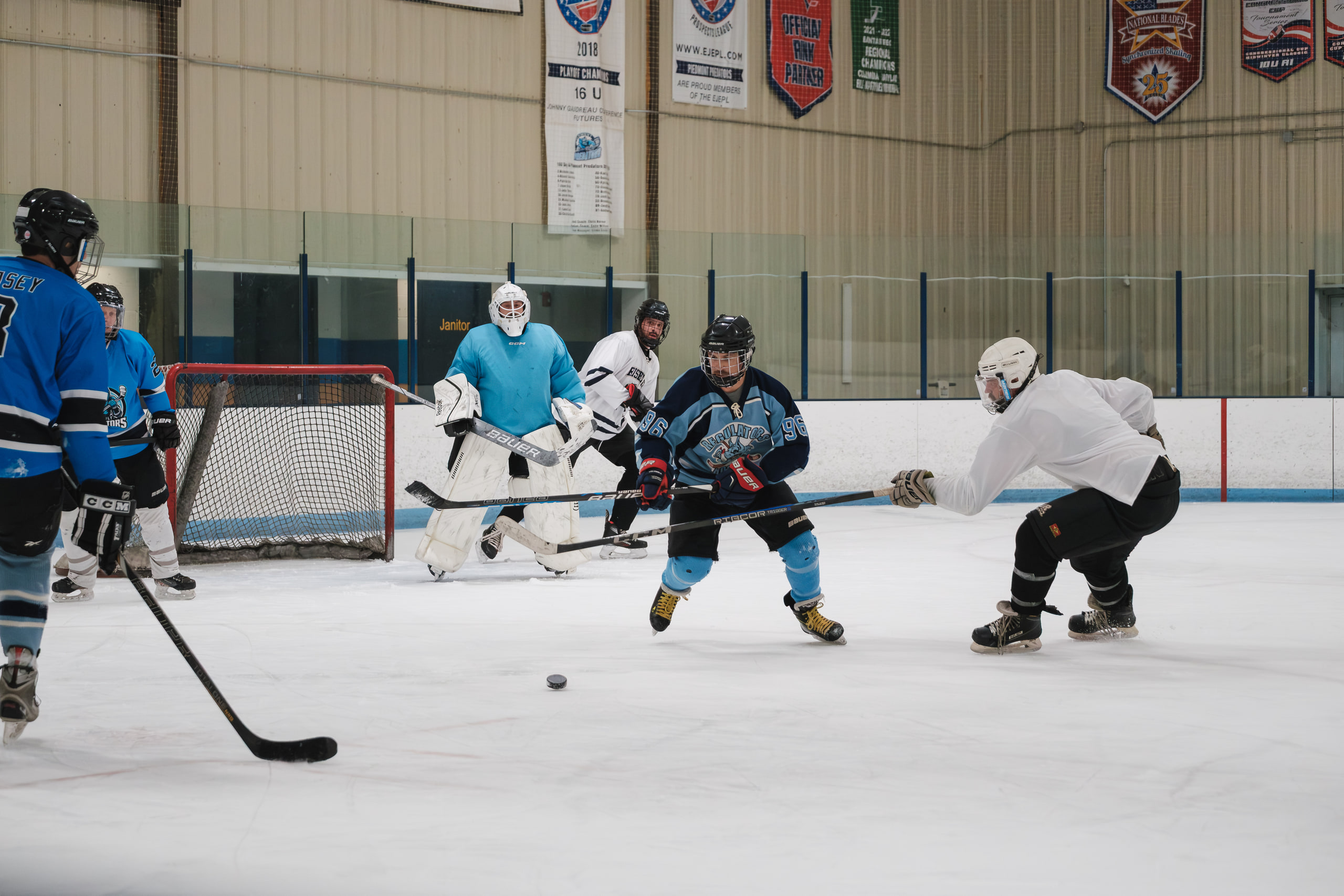 A scrum in front of the net during a league hockey game.