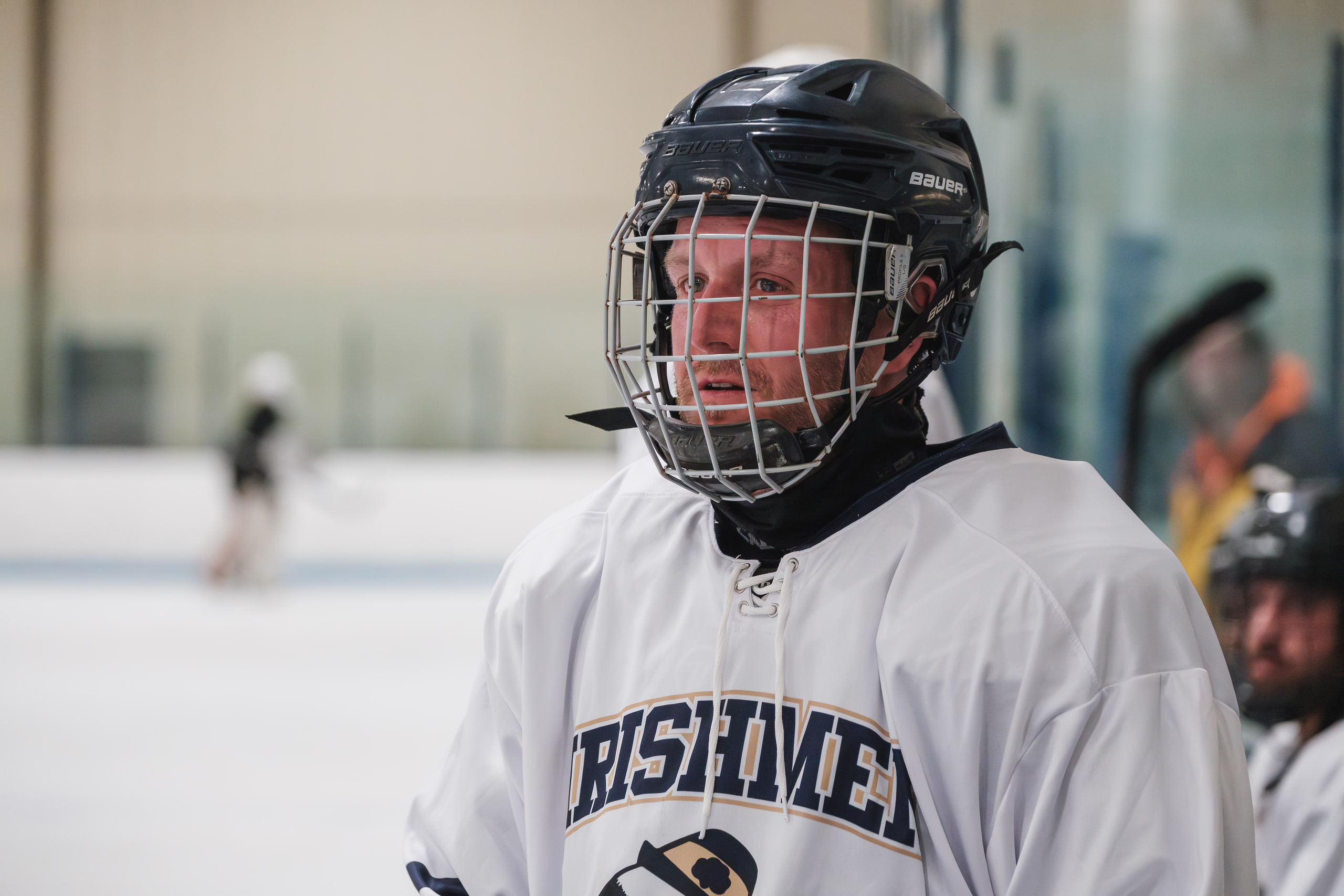 A hockey player looking straight at the camera through the cage.