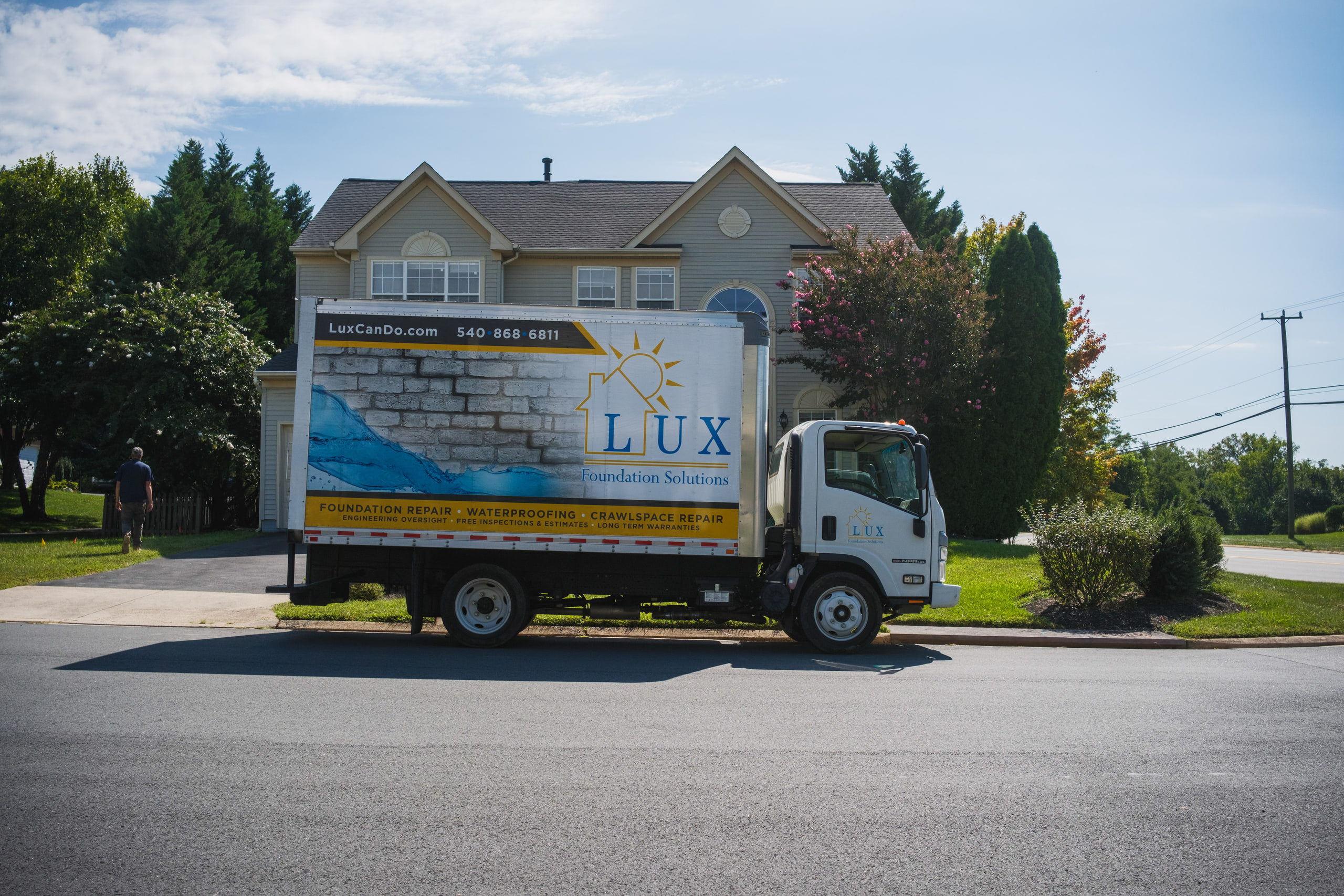 A box truck arriving on a suburban street for a foundation repair job.