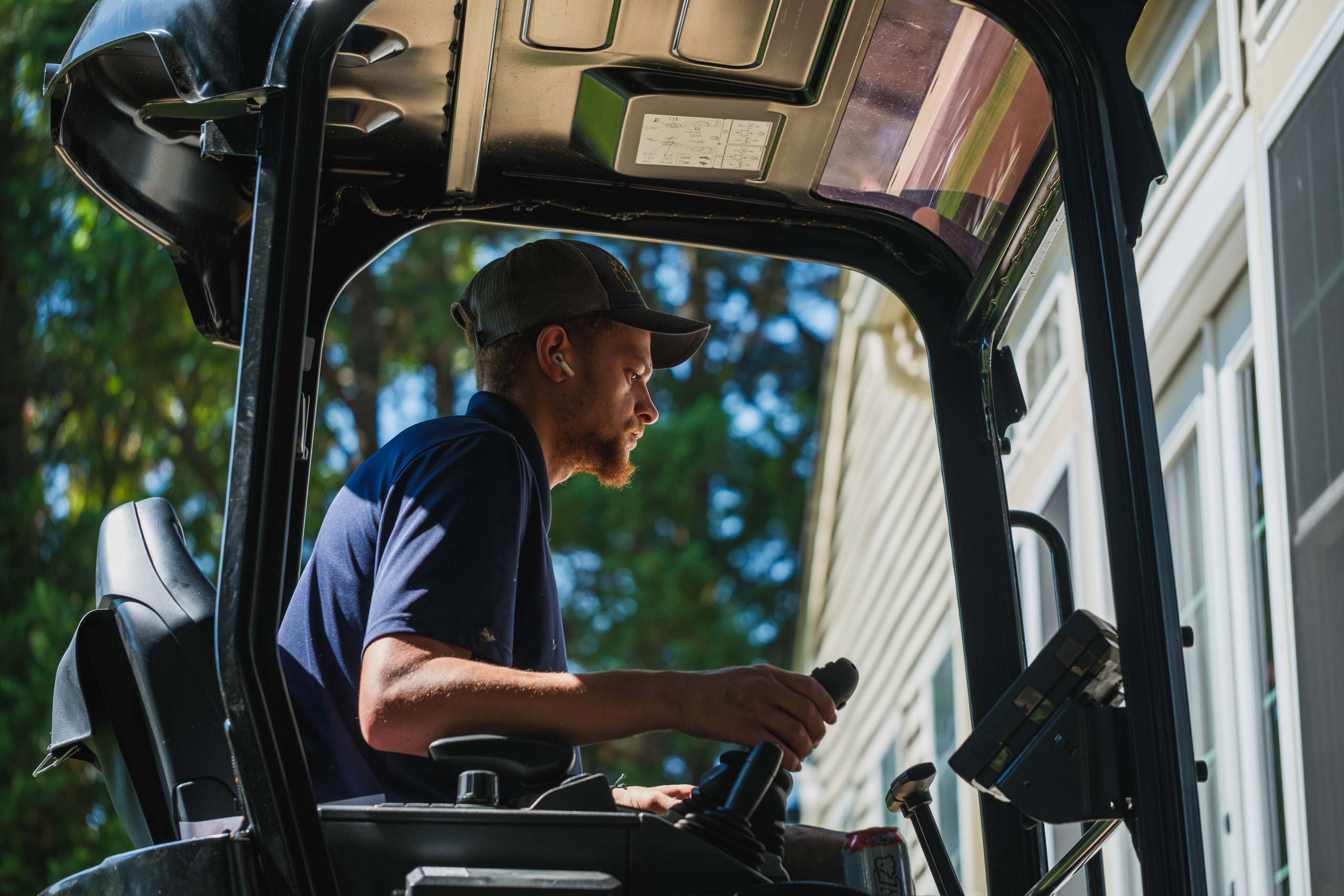 An excavator operator in the cab, in profile, on a foundation repair job.