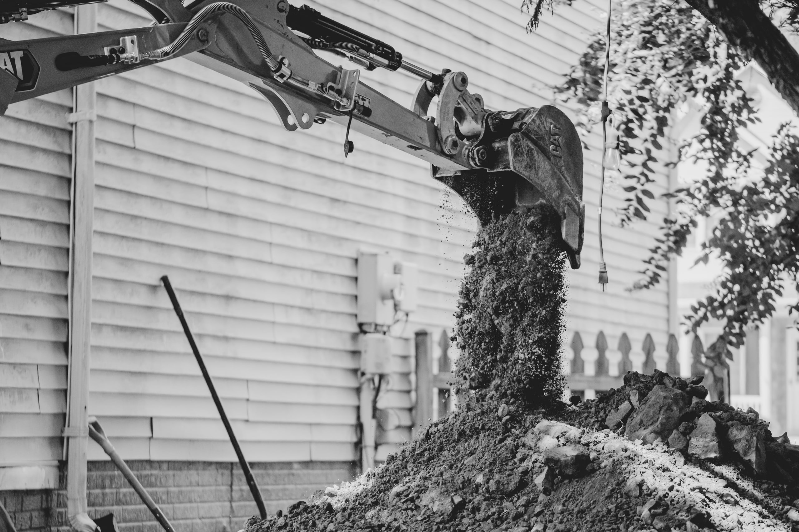 An excavator arm over a foundation trench, black and white.