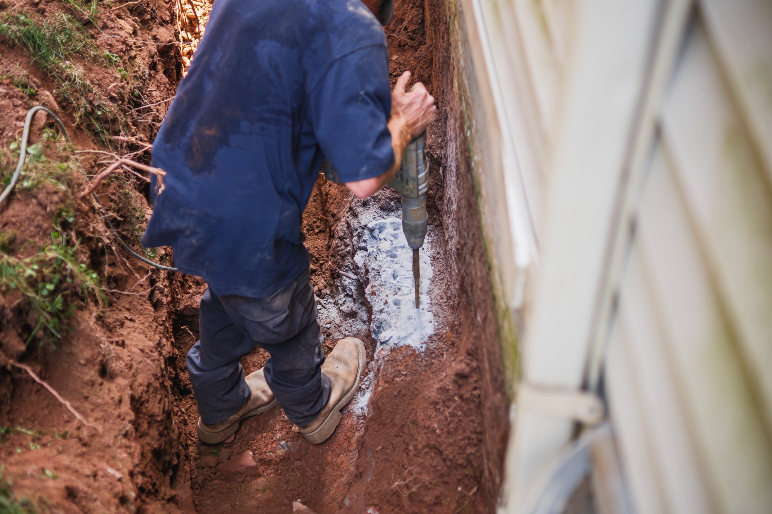 Gloved hands working in the dirt at a house footing.