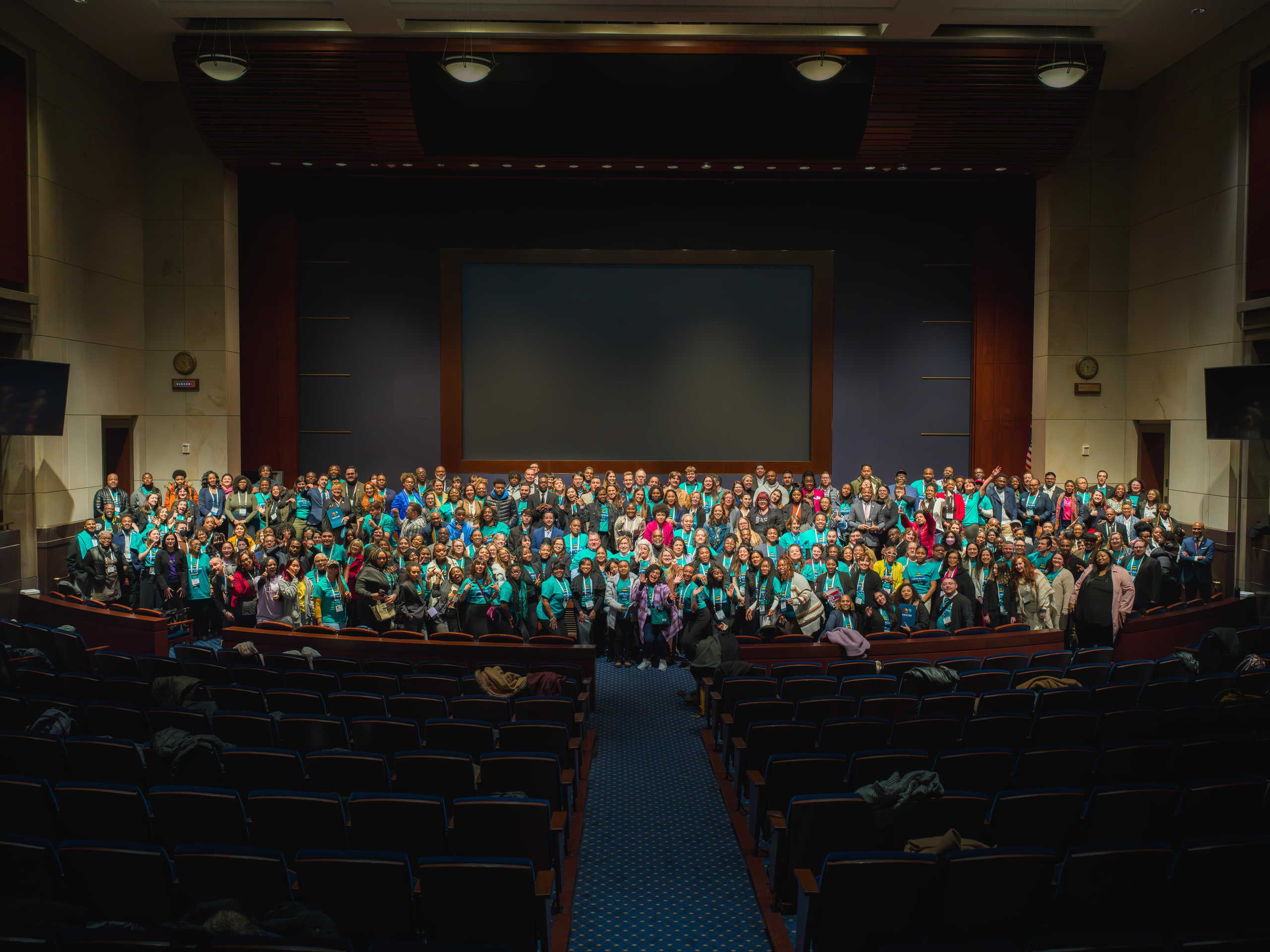 Auditorium wide, teal crowd, scale at a Capitol Hill day in Washington, DC.