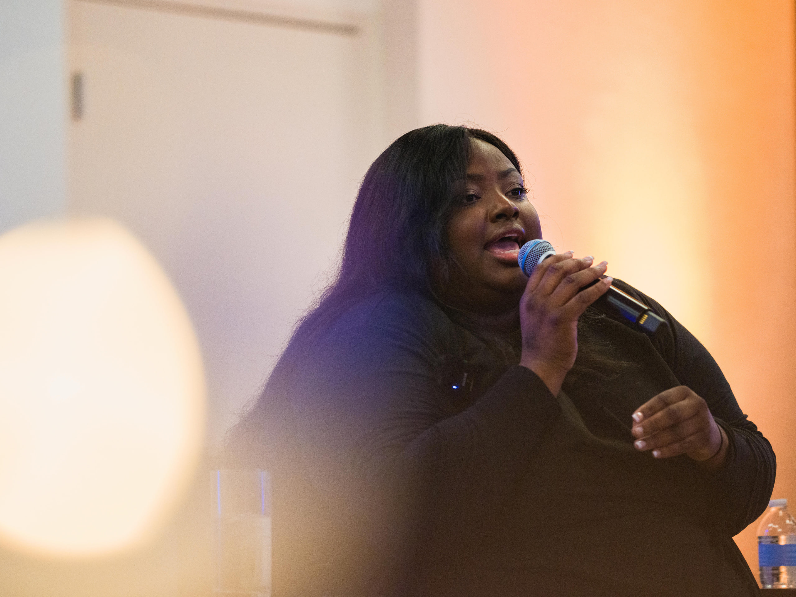 Panelist singing into the mic, warm bokeh at a summit campfire session.