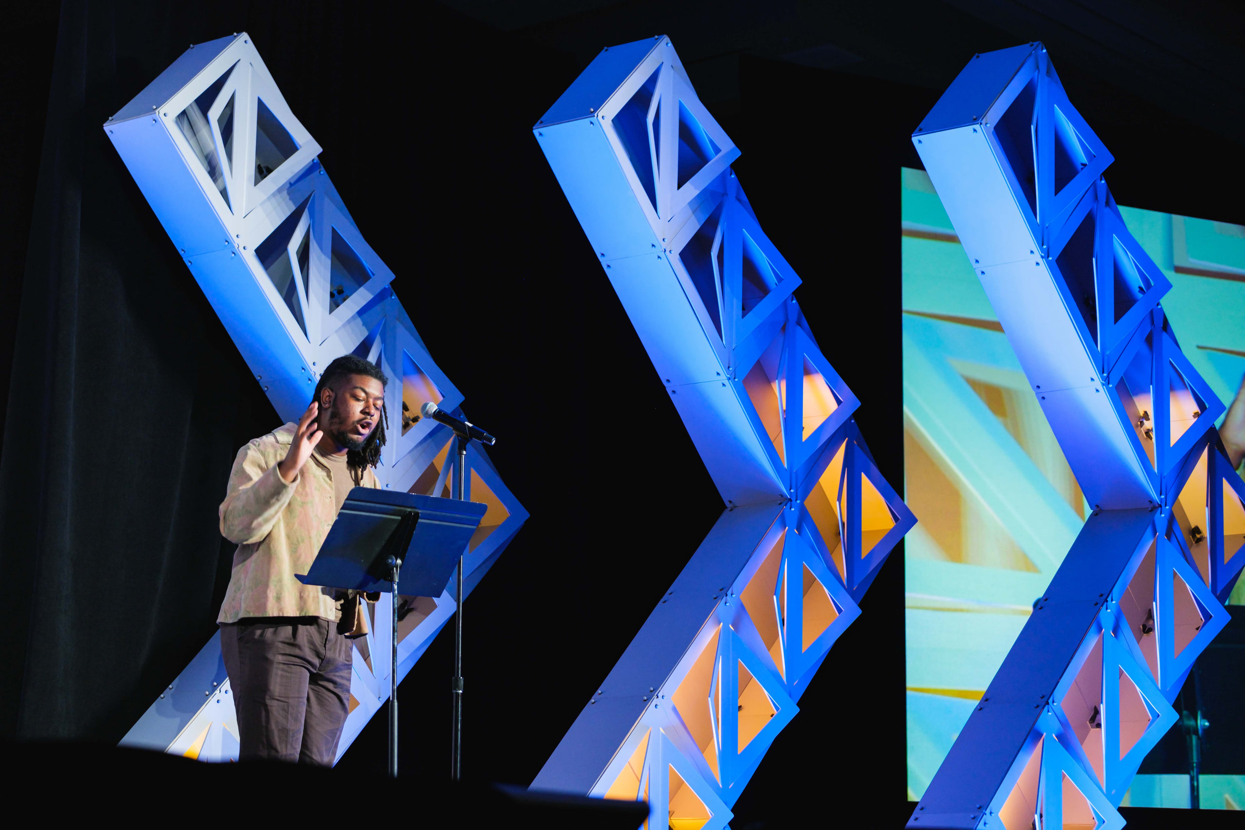 Singer small inside the chevrons at a national summit opening plenary.